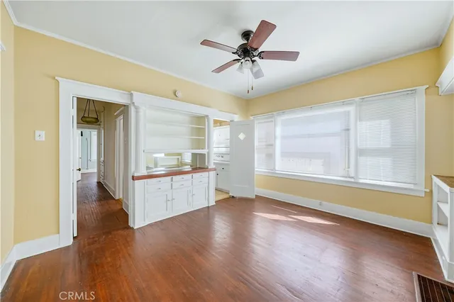 a view of an empty room with window and wooden floor