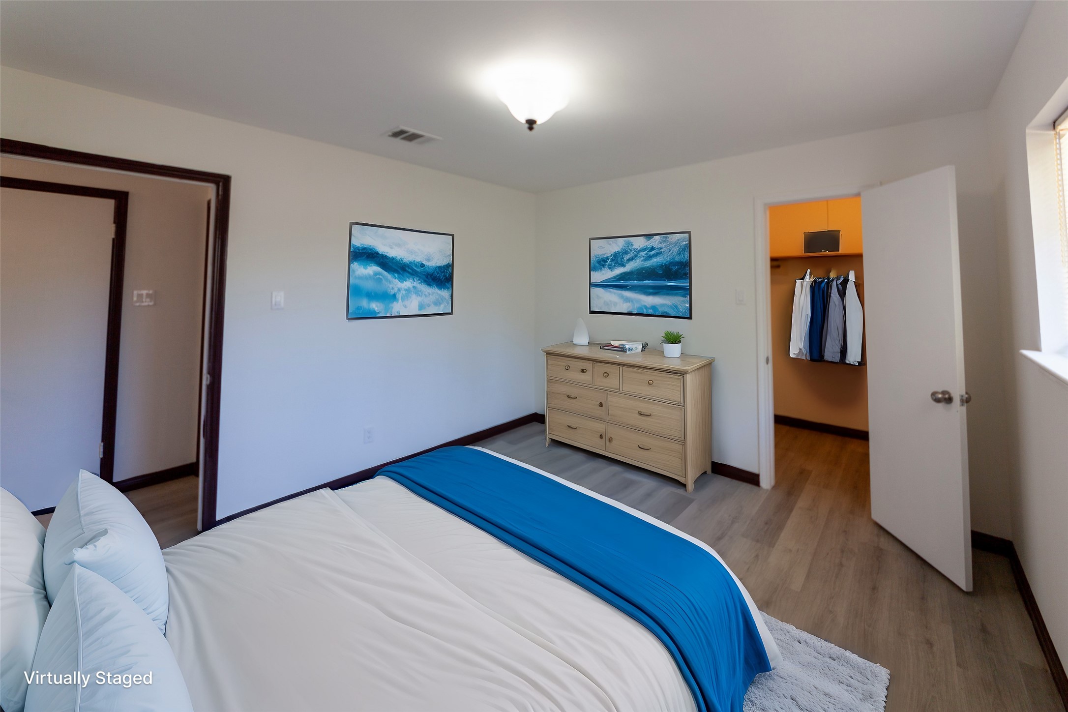 8826 Roos Road Houston, TX 77036 - Photo 21 of 42 A bright, virtually staged bedroom 3 with a cozy bed, modern decor, and a spacious walk-in closet. Light wood flooring and neutral walls provide a clean, welcoming atmosphere.