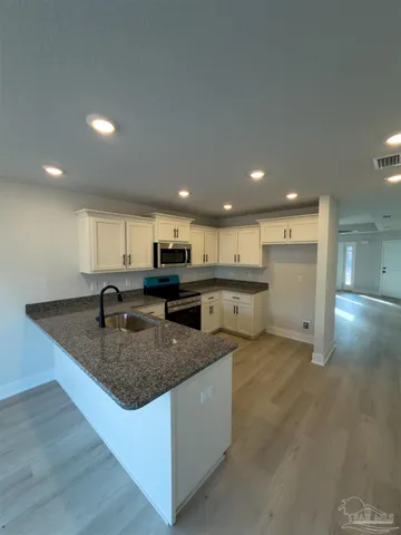 a large kitchen with a counter top space a sink and cabinets