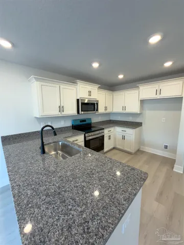 a kitchen with granite countertop a stove a sink and a microwave