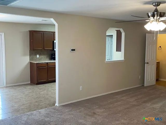 an empty room with chandelier fan and windows