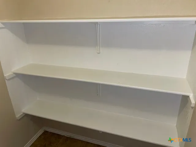 an empty room with wooden floor and fan