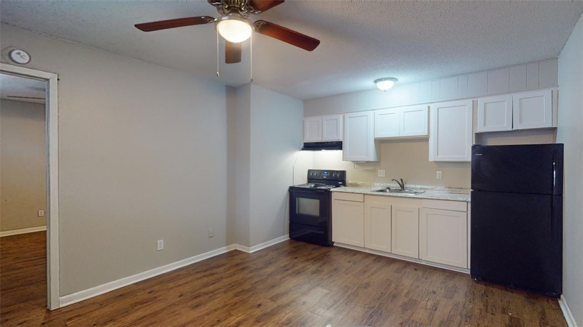 500 Foch Street, Unit 11 Bryan, TX 77801 - Photo 2 of 11 a kitchen with stainless steel appliances granite countertop a refrigerator a sink dishwasher a stove and white countertops with wooden floor