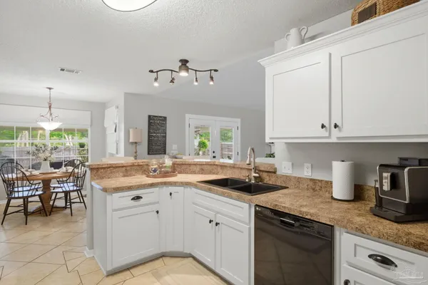 a kitchen with a sink dishwasher a stove and white cabinets with wooden floor