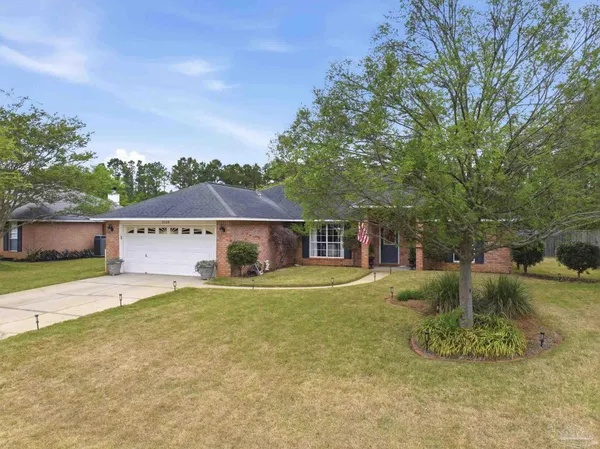 a view of a house with a yard and large tree