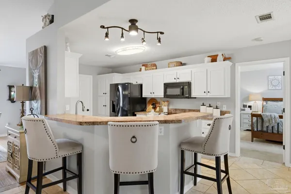a kitchen with stainless steel appliances kitchen island granite countertop a table chairs and a refrigerator