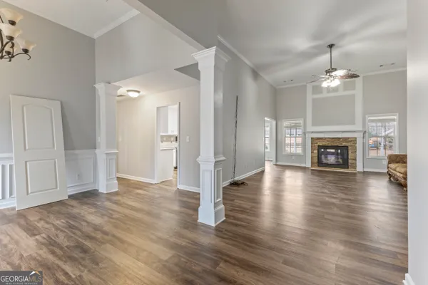 an empty room with wooden floor fireplace and windows
