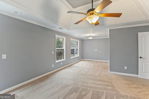 a view of an empty room with chandelier fan and a window