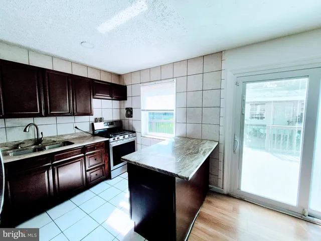 a kitchen with granite countertop stainless steel appliances a stove sink and cabinets