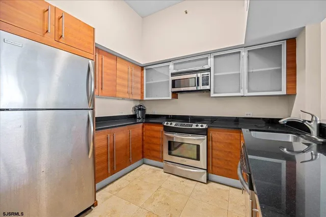 a kitchen with stainless steel appliances granite countertop a refrigerator a stove a sink and a microwave