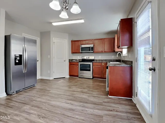 a kitchen with stainless steel appliances granite countertop a refrigerator a stove a sink and dishwasher with wooden floor