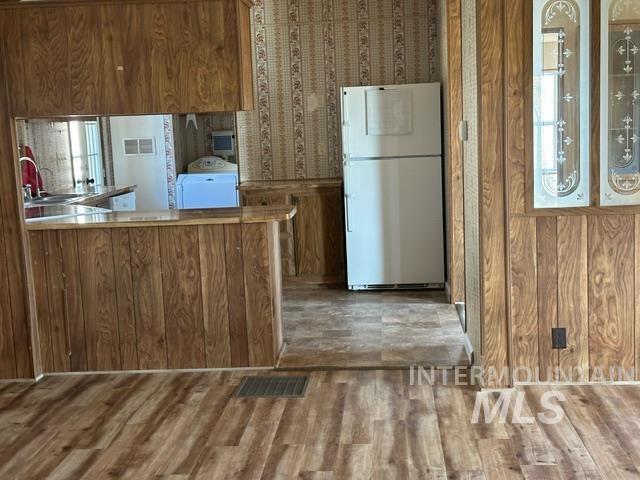 4417 Oak Road Ontario, OR 97914 - Photo 33 of 50 Kitchen featuring freestanding refrigerator, brown cabinets, light countertops, a peninsula, and wallpapered walls