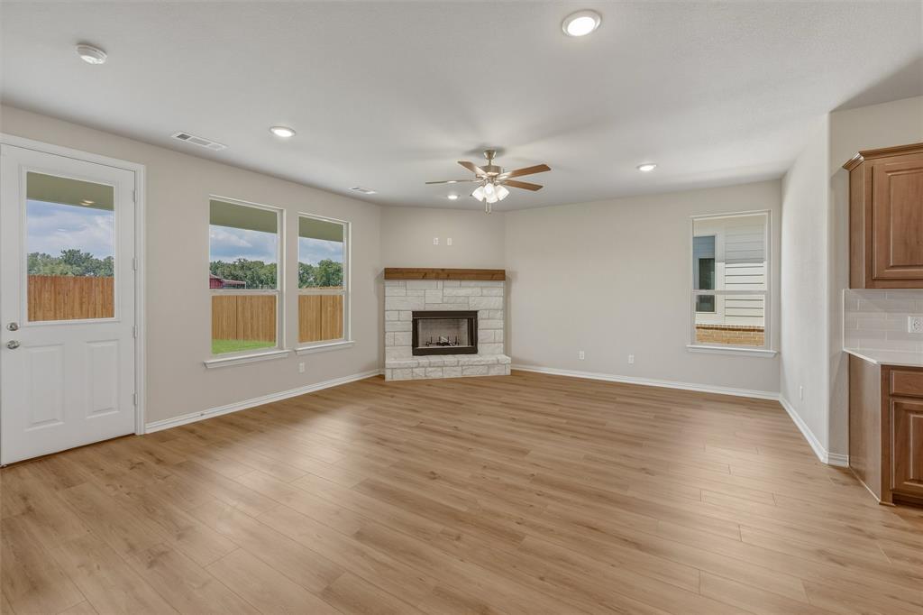 1232 Colca Drive Springtown, TX 76082 - Photo 6 of 23 Open-concept living space featuring wood-finish flooring, a stone fireplace with a wood mantle, recessed lighting, a ceiling fan, and multiple windows