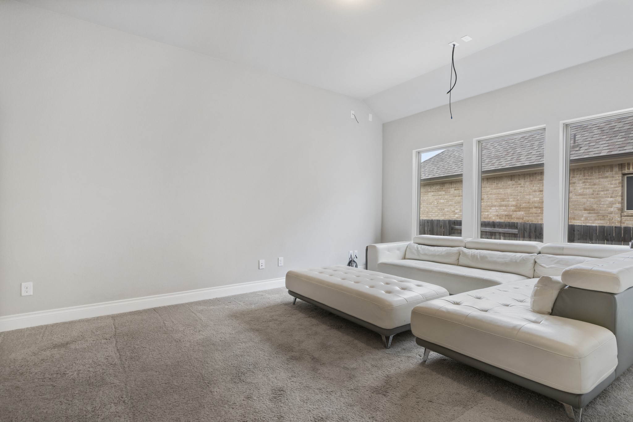104 Catani Loop Georgetown, TX 78628 - Photo 15 of 34 Living room featuring light-colored walls, carpeted flooring, and a large window with views of a brick exterior