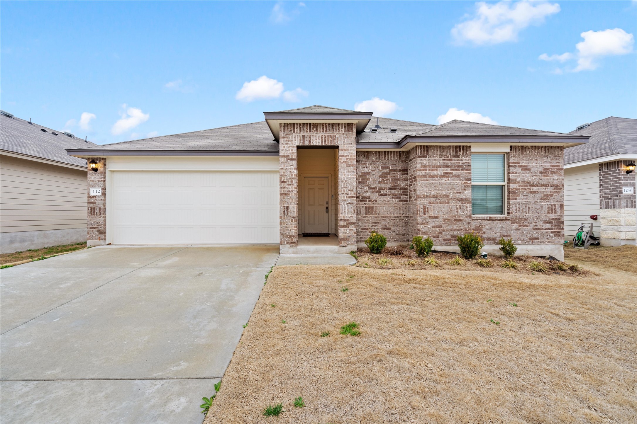 112 Ragnar Drive Jarrell, TX 76537 - Photo 1 of 1 Brick veneer exterior with a covered entry, attached garage, and a concrete driveway