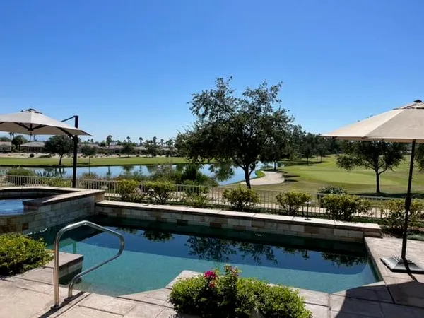 a view of a swimming pool and lounge chairs in back yard of a house