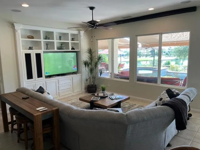 a living room with furniture a flat screen tv and a large window