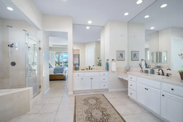 a large bathroom with a double vanity sink a large mirror and a bathtub