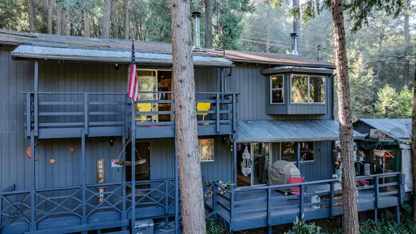 a view of a wooden house with a small yard and large tree