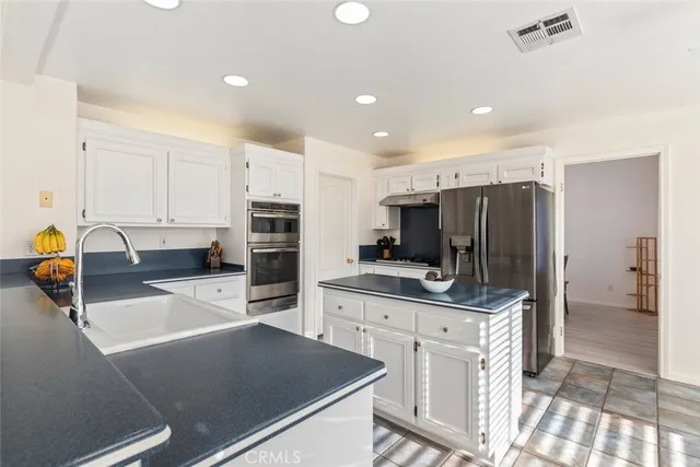 a kitchen with stainless steel appliances a stove a sink a refrigerator a counter top space and cabinets