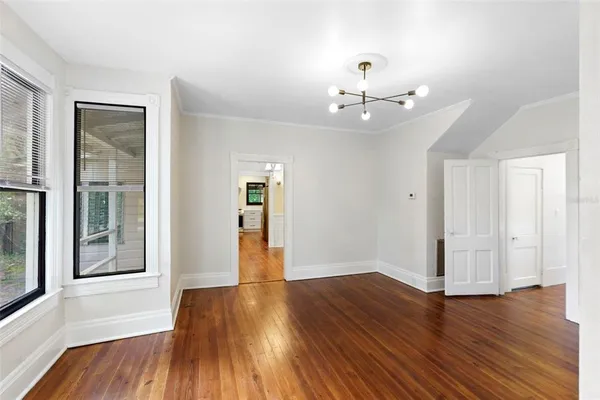 a view of an empty room with wooden floor and a window