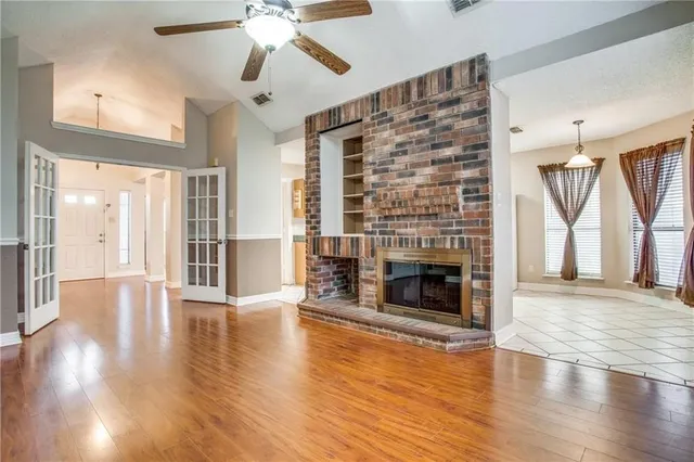 a view of a livingroom with wooden floor a ceiling fan and a fireplace