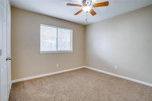 an empty room with chandelier fan and windows
