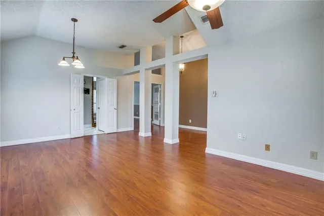 an empty room with wooden floor ceiling fan and window