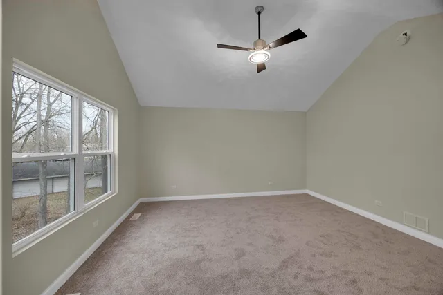 an empty room with a chandelier fan and windows