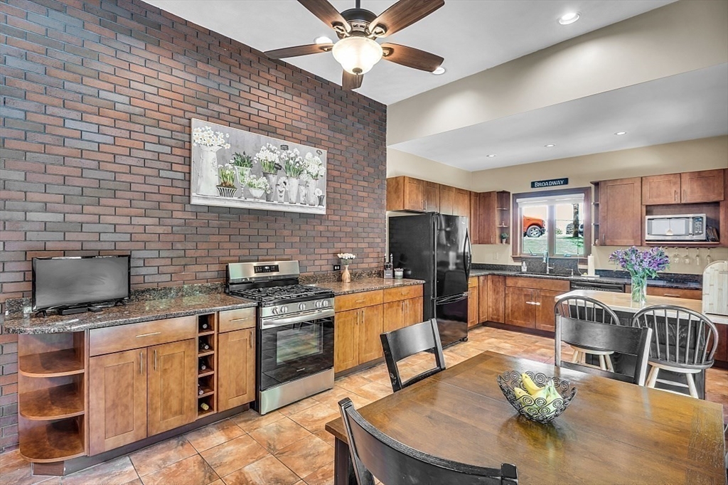 17 Berkshire Road Peabody, MA 01960 - Photo 14 of 41 a kitchen with stainless steel appliances kitchen island granite countertop a stove a sink dishwasher a dining table and chairs with wooden floor