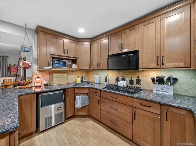 a kitchen with granite countertop wooden cabinets stainless steel appliances a sink and a window