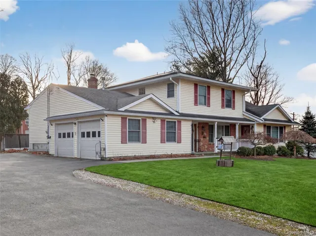 a front view of a house with a garden and trees