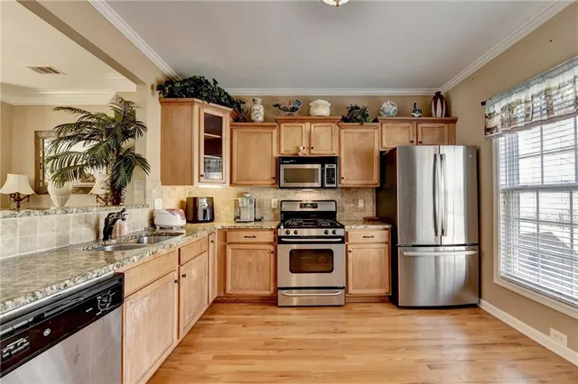 a kitchen with stainless steel appliances granite countertop a refrigerator a sink a stove a microwave and cabinets