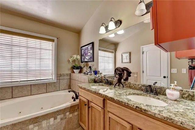 a bathroom with a granite countertop sink a large mirror and bathtub