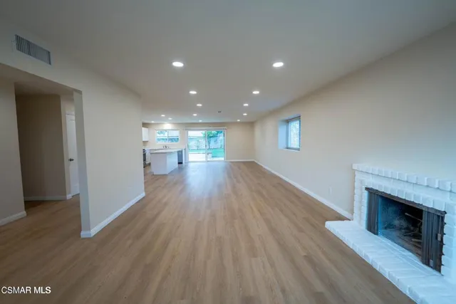 a view of empty room with wooden floor and fireplace