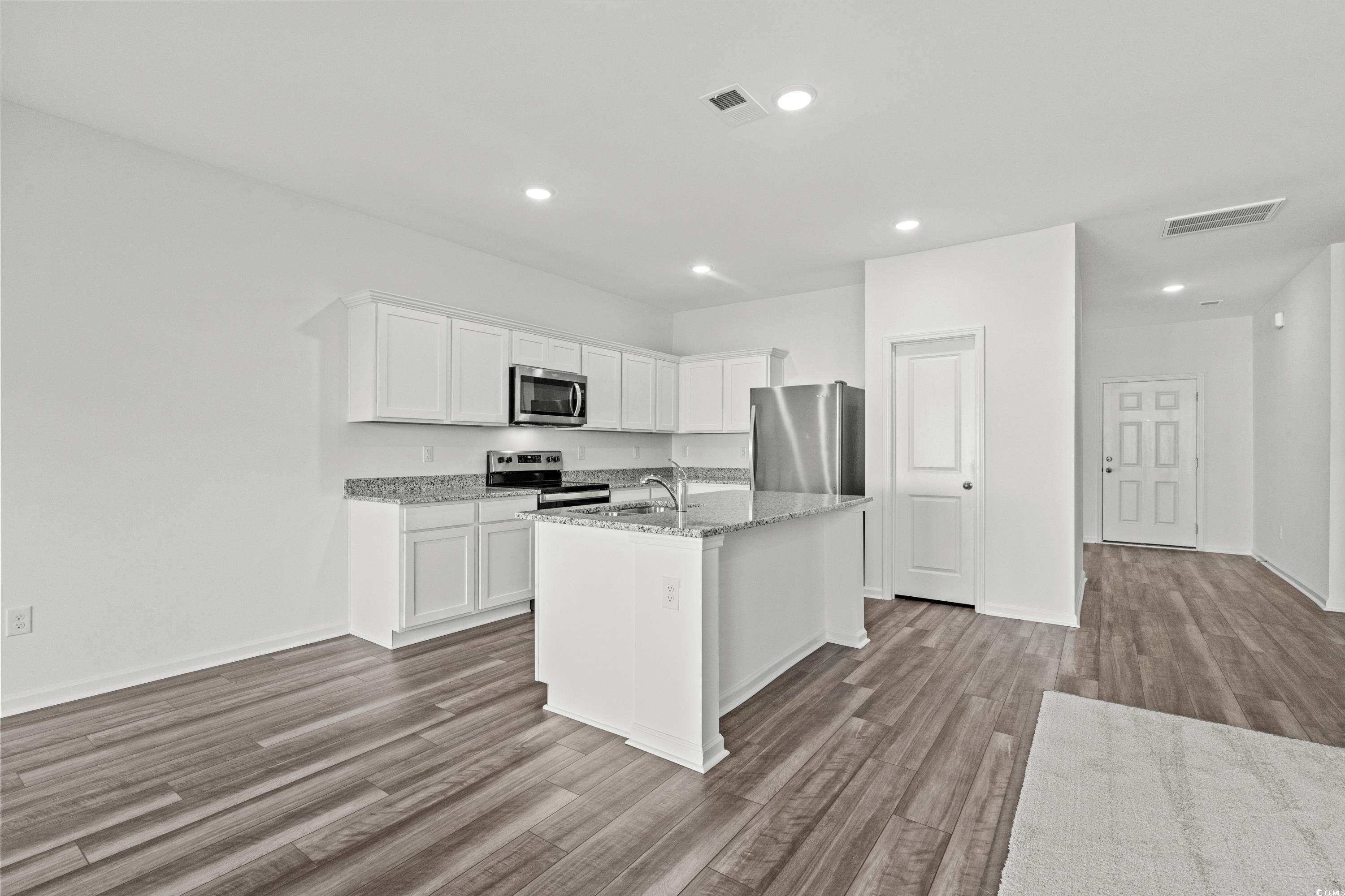 443 Castillo Drive Longs, SC 29568 - Photo 12 of 32 Kitchen featuring white cabinetry, stainless steel appliances, a kitchen island with sink, light stone counters, and light wood-type flooring