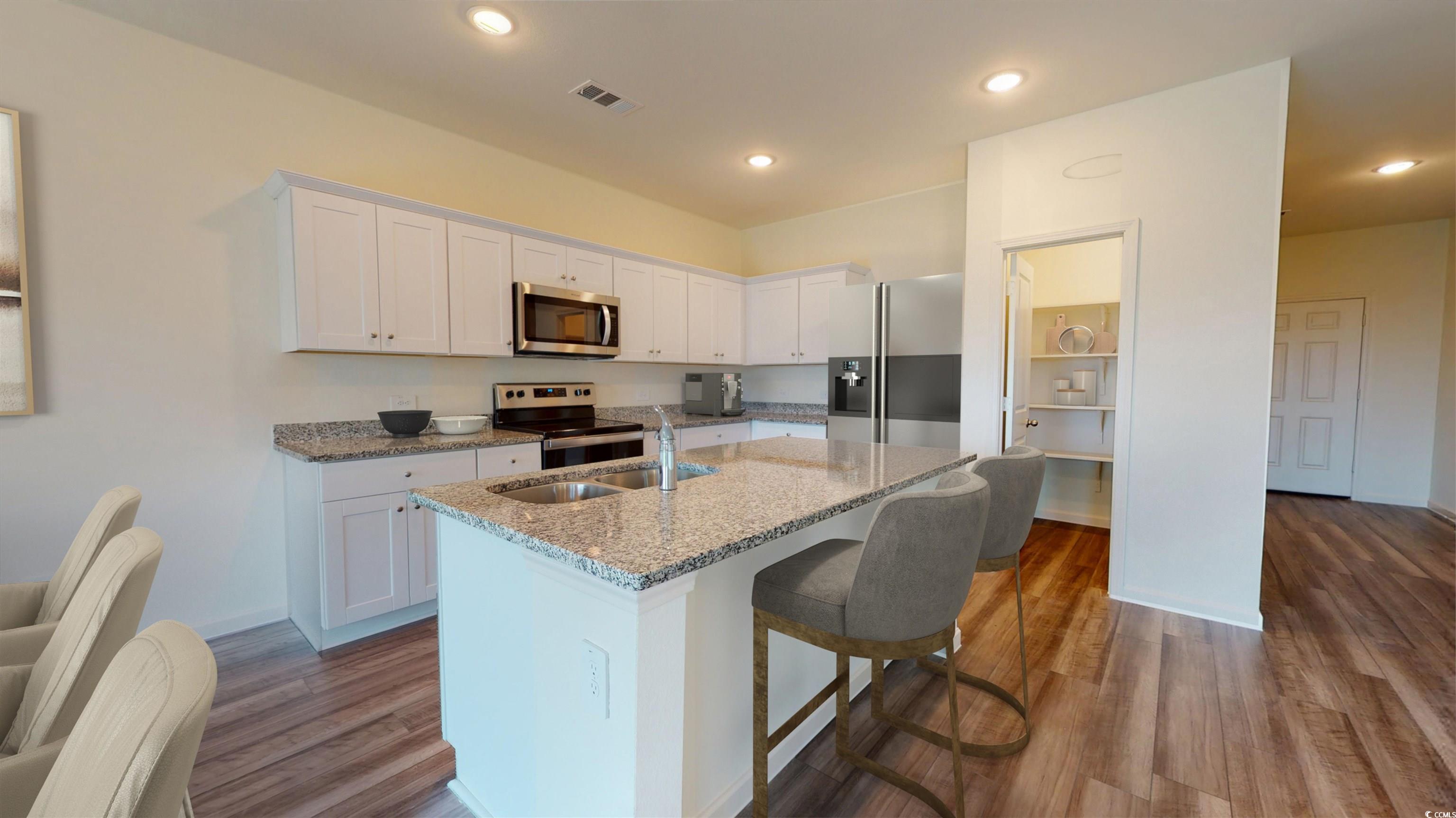 443 Castillo Drive Longs, SC 29568 - Photo 9 of 32 Kitchen featuring white cabinetry, light stone counters, appliances with stainless steel finishes, a breakfast bar, and a kitchen island with sink