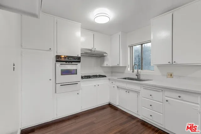 a kitchen with granite countertop white cabinets and white appliances