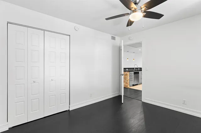an empty room with wooden floor cabinet and windows