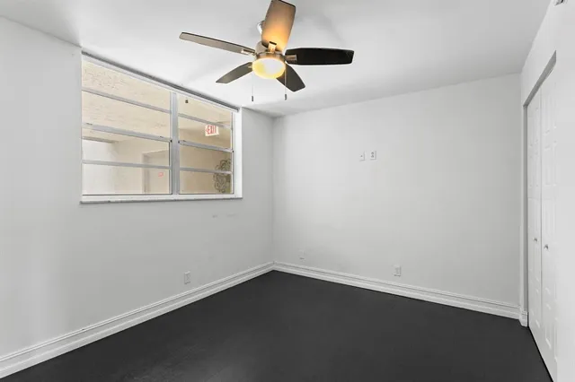 an empty room with a window and a ceiling fan