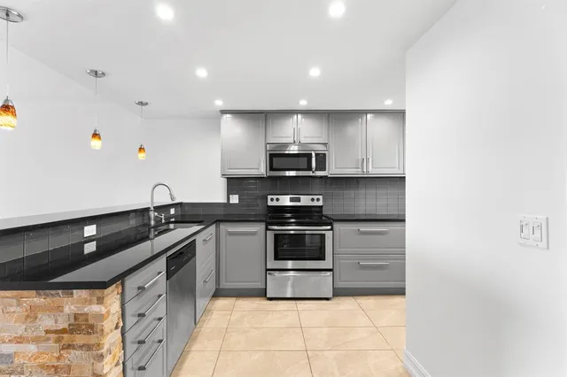 a kitchen with stainless steel appliances granite countertop a sink and a stove
