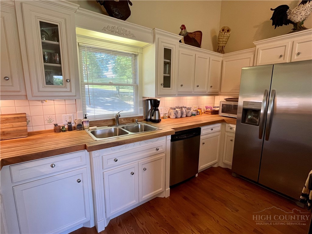 638 Ridge Road Glade Valley, NC 28627 - Photo 13 of 44 a kitchen with a sink dishwasher and white cabinets with wooden floor