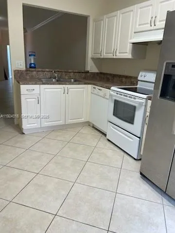 a kitchen with granite countertop white cabinets and appliances