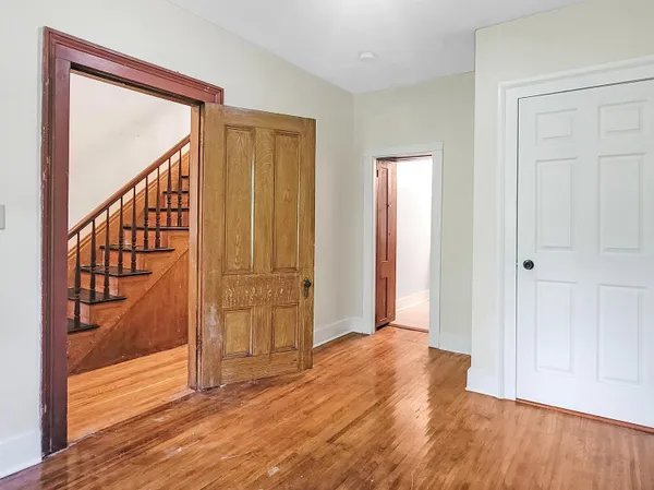 a view of an empty room with wooden floor and a window