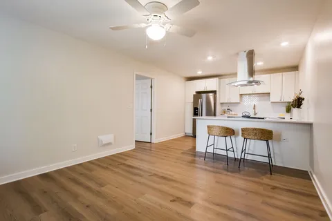 a kitchen with kitchen island stainless steel appliances a dining table chairs sink and cabinets