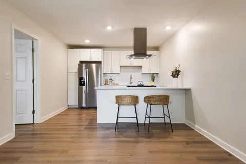 a kitchen with kitchen island granite countertop a sink cabinets and wooden floor