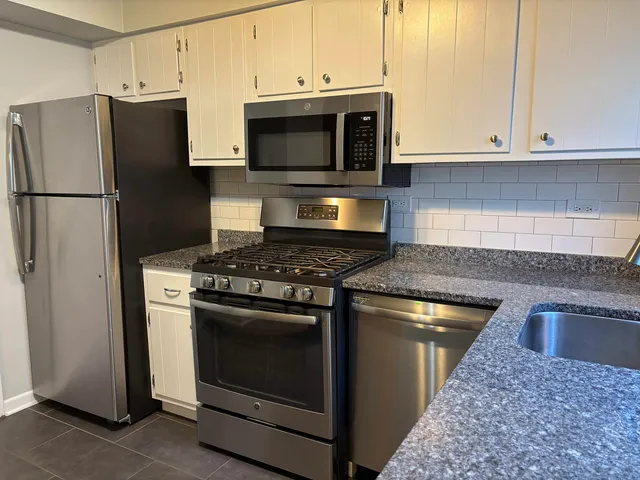 a kitchen with granite countertop a stove microwave and refrigerator