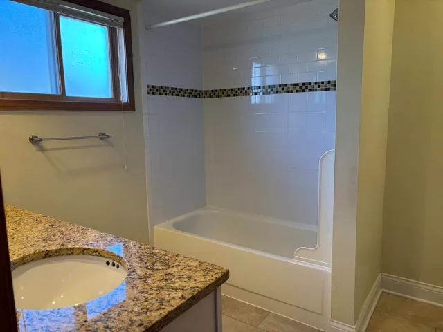 a bathroom with a granite countertop sink and a bathtub