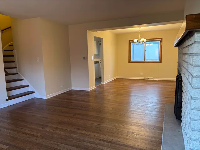 a view of an empty room with wooden floor and a fireplace