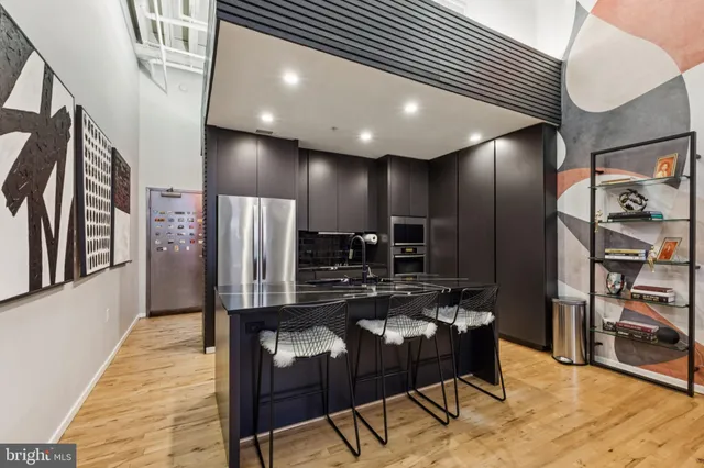 a kitchen with stainless steel appliances kitchen island granite countertop a refrigerator a stove and a sink with wooden floor